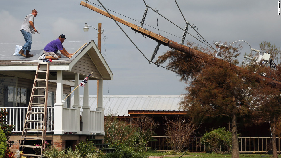 Workers repair the roof of a home as downed power lines caused by Hurricane Isaac lean onto a tree in lower Plaquemines Parish on Sunday, September 2.