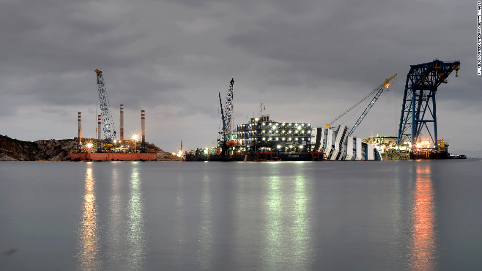 Cranes and floating decks surrounding the ship light up the dusk on Wednesday.