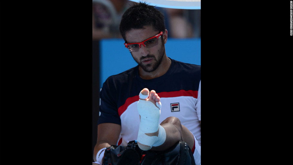 Serbia's Janko Tipsarevic looks at his wrapped foot during a break in his men's singles match against Spain's Nicolas Almagro on January 20. Almagro moved on to the next round after Tipsarevic pulled out of the match in the second set because of his injury.