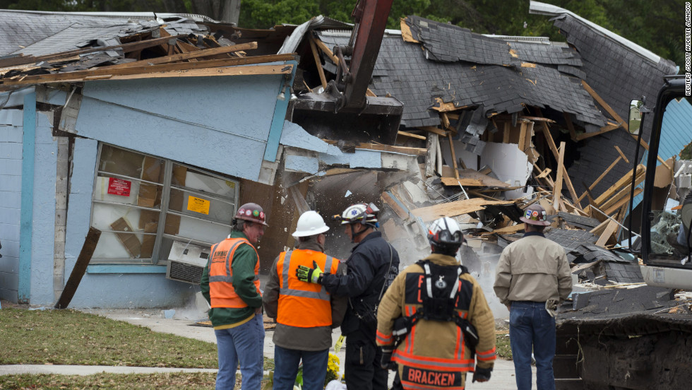 Workers watch the demolition of the house where a sinkhole opened three days before in Seffner, Florida, on March 3. Sinkholes caused by acidic groundwater corroding the limestone or carbonate rock underground are common in Florida, according to the Florida Department of Environmental Protection.