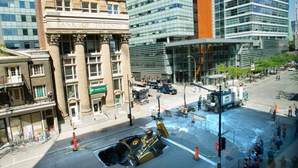 A backhoe is swallowed by a sinkhole in Montreal, Quebec, Canada, on August 6. The driver of the backhoe was not injured.