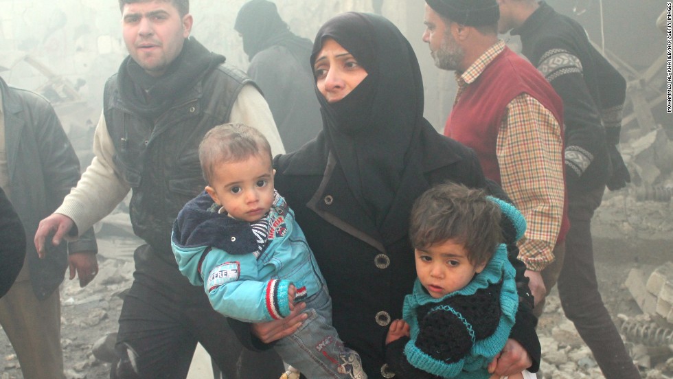 A Syrian woman carries children following airstrikes on Aleppo.