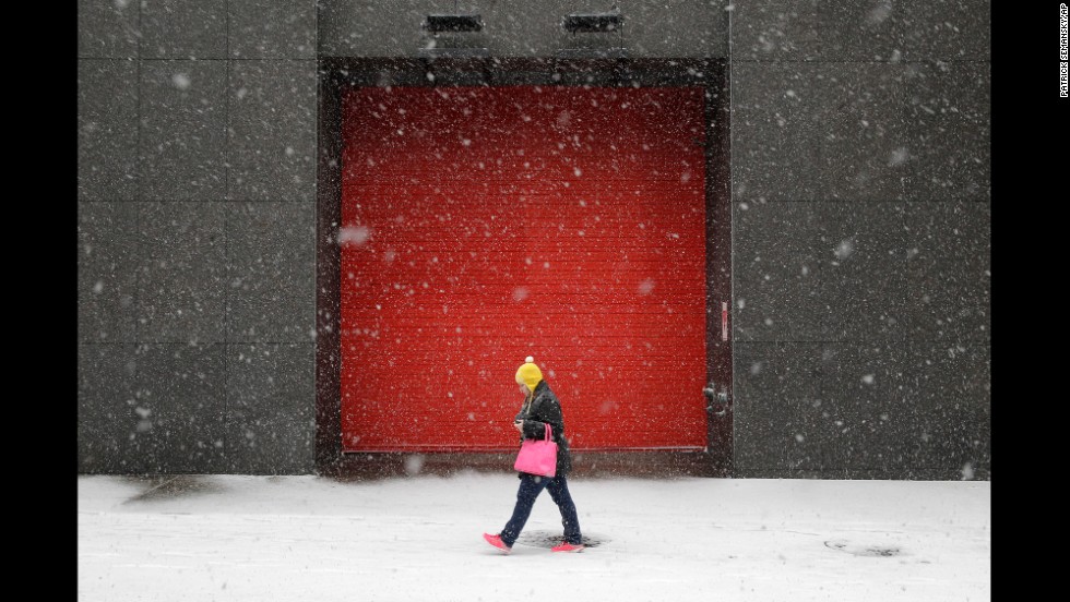 A woman walks in Baltimore as snow falls Tuesday, January 21.