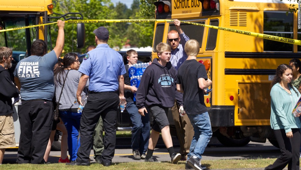 Buses arrive at a grocery store parking lot in Wood Village on June 10 to reunite students with their parents after the shooting.