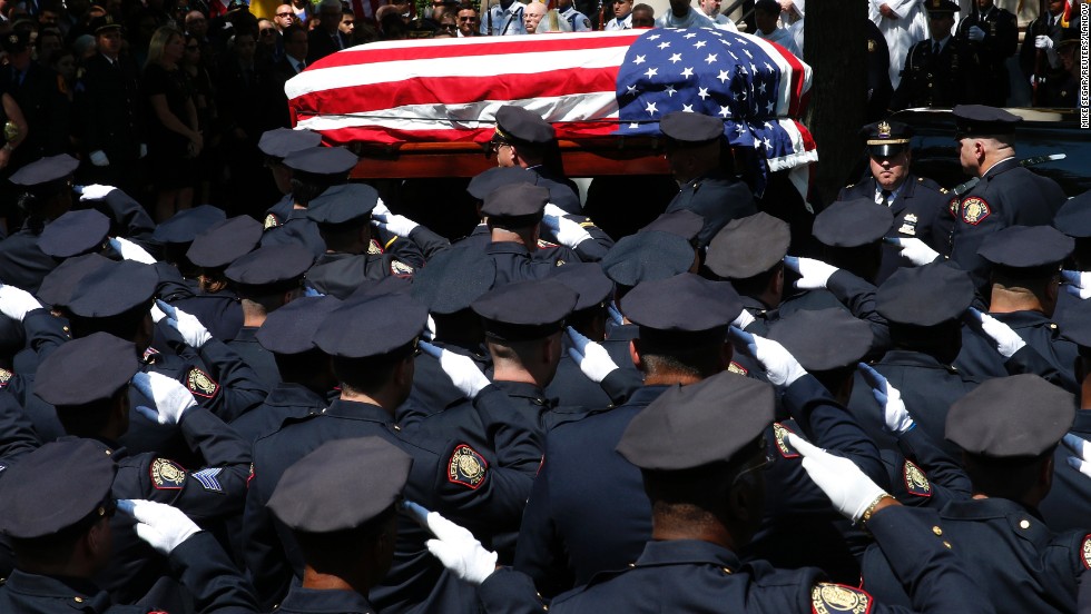 Police officers salute as the casket carrying slain police officer Melvin Santiago is carried into a church for his funeral service in Jersey City, New Jersey, on Friday, July 18. Santiago was shot and killed in his car after responding to an armed robbery call, officials said.