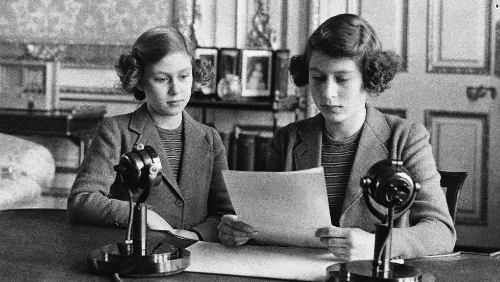 A 14-year-old Princess Elizabeth, right, sits next to her sister for a radio broadcast on October 13, 1940. On the broadcast, her first, she said that England&#39;s children were full of cheerfulness and courage.