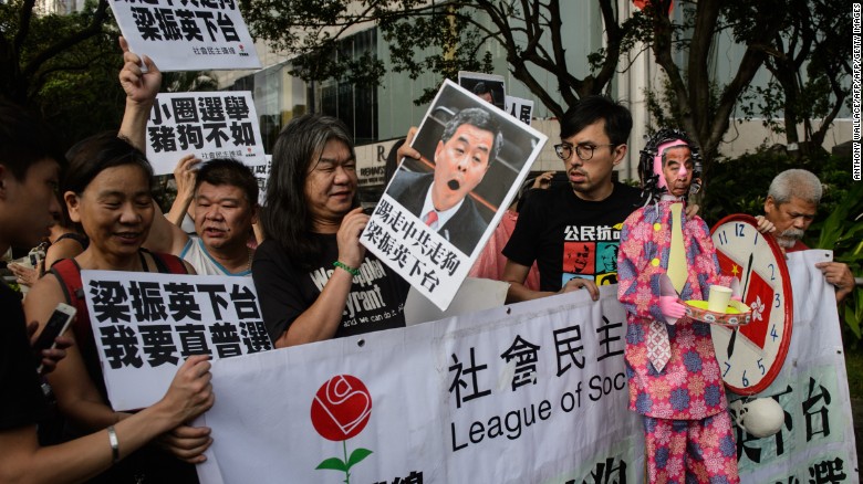 Protesters hold signs ahead of a mass march through central Hong Kong on Friday, July 1, 2016.