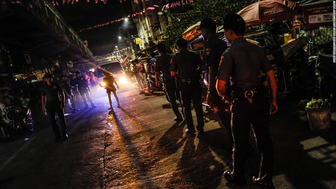 Police patrol a shanty community at night during curfew on June 8, 2016 in Manila.