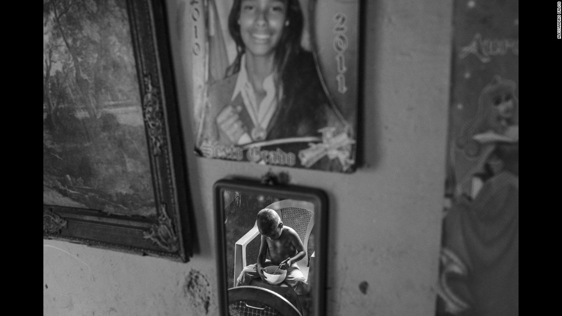 A child eats a meal offered by his neighbor in Caracas.