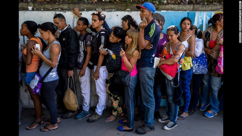 People line up to buy basic food and household items outside a supermarket in Caracas, on September 28, 2016.