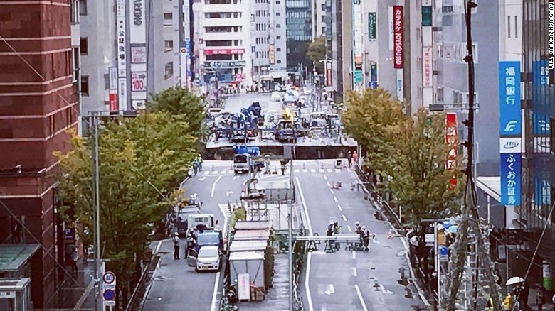 A giant sinkhole has opened up in Fukuoka, Japan, swallowing huge sections of road including traffic lights, near to underground work to extend a subway tunnel.  Will Barker was close to Hakata Station and captured this image, showing emergency vehicles blocking access to the road.  He told CNN: The hole was interesting, so I went to investigate.