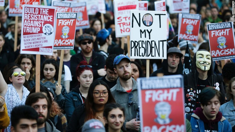 People in downtown Seattle carry signs and listen to speakers in a protest against President-elect Donald Trump.. 