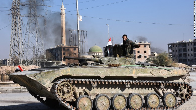 A Syrian soldier on Monday drives a tank through an area of eastern Aleppo recently seized by the regime.