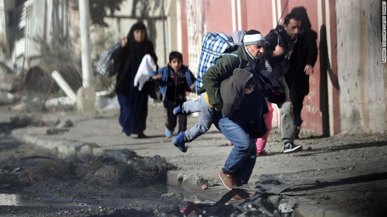 Iraqis run for cover as ISIS fighters clash with government forces last week in northeastern Mosul.