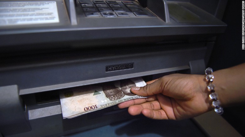 A customer withdraws Nigerian naira from an automated teller machine (ATM) at a bank in Asaba, Delta State.