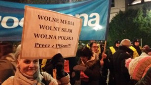 A woman holds a sign reading &quot;Free media, free parliament, free Poland&quot; during Friday&#39;s protest outside the legislature.