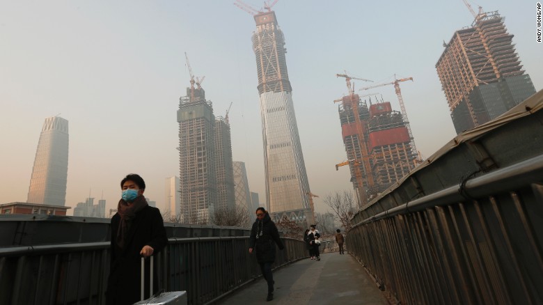 A person wears a mask while crossing a bridge in Beijing on Monday, December 19. A gray haze of smog descended on Northeast China over the weekend, and China has issued a red alert for 23 cities.