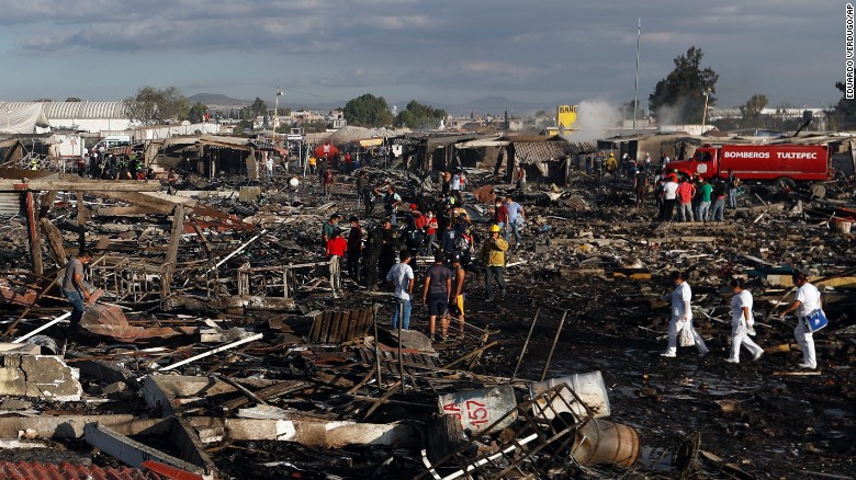 Firefighters and rescue workers walk through the fireworks market after the explosion.