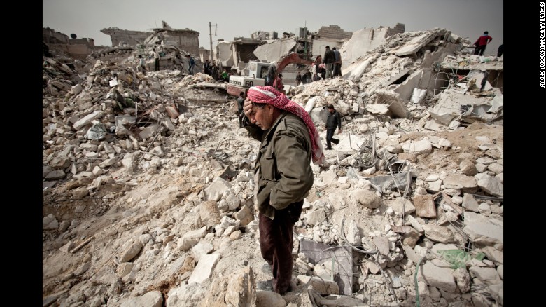 A Syrian man reacts while standing on the rubble of his house while others look for survivors and bodies in the Tariq al-Bab district of the northern city of Aleppo on February 23, 2013.