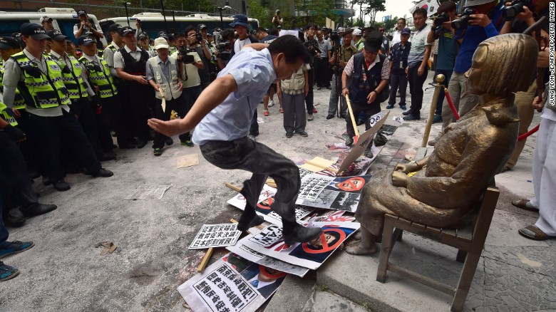 A protester tramples photos of Japanese Shinzo Abe in front of a state memorializing Korean WWII sex slaves, also known as &quot;comfort women.&quot; 
