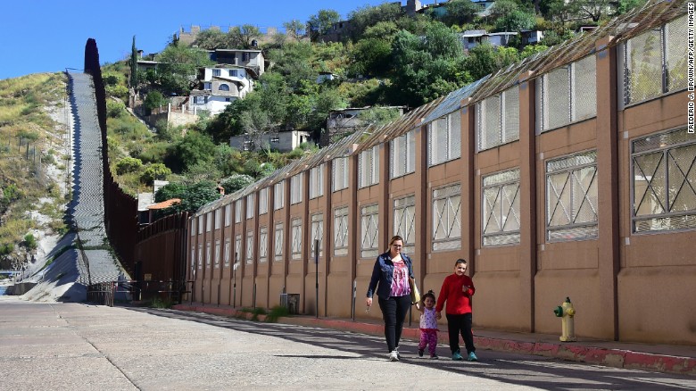 A woman and children walk beside the border wall and fence separating the United States from Mexico on October 11, 2016 in Nogales, Arizona, across the border barrier from Nogales, Sonora. 