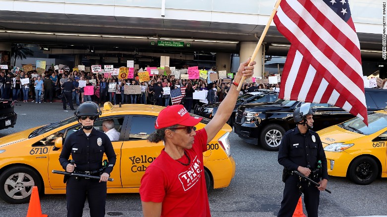 A President Trump supporter waves a US flag at Los Angeles International Airport during a demonstration Sunday over the immigration ban.