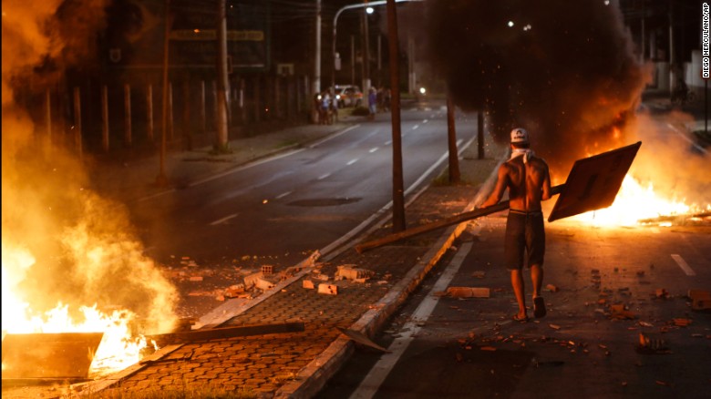 A man carries a sign to throw on a barricade.