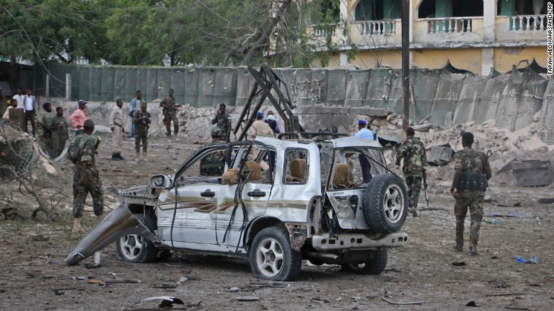 Somali soldiers stand near the wreckage of a car bomb attack in Mogadishu.