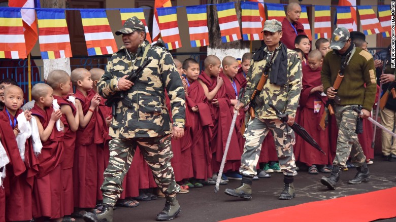 Indian security personnel walk past Buddhist monks as they wait for the Dalai Lama in Bomdila in India&#39;s northeastern state of Arunachal Pradesh on April 4, 2017.