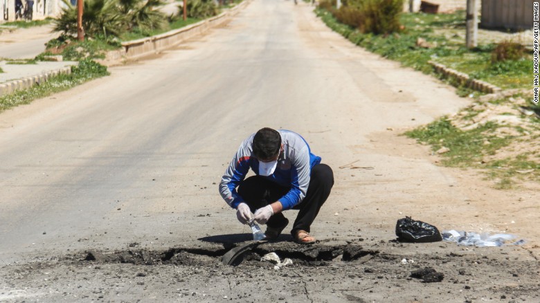 Un uomo raccoglie campioni dal cratere di impatto dell'ordigno contenente il gas sarin, Khan Shaykhun (Idlib). Credits to: Omar Haj Kadour/AFP.
