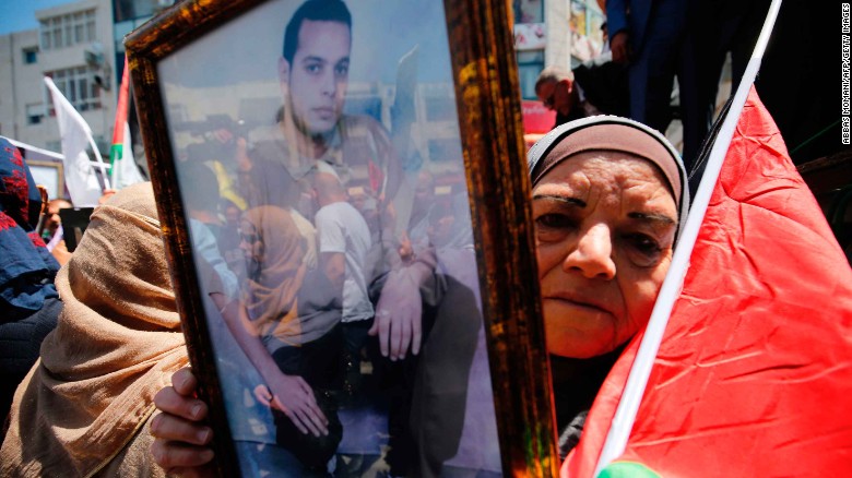 A woman holds the portrait of a Palestinian prisoner during a rally in Ramallah Monday.