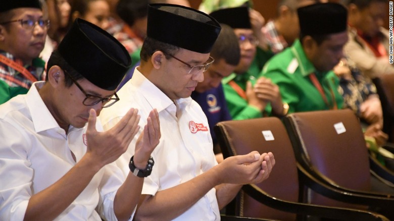 Anies Baswedan (2L) and his running mate pray during an event in Jakarta on March 4.