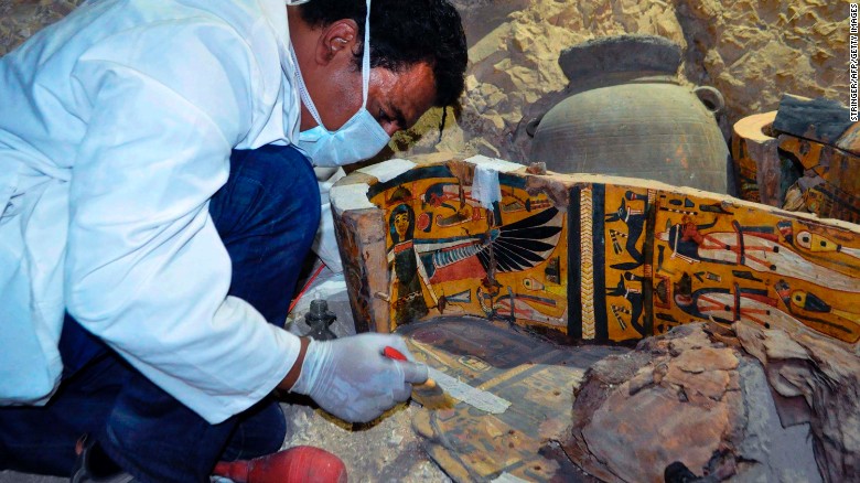 A member of the Egyptian archaeological team works on a wooden coffin Tuesday.