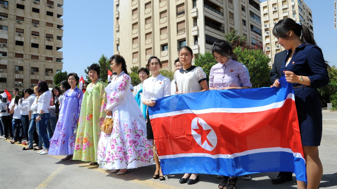 Youngwomen hold a North Korean flag during a ceremony to name a park in Damascus after Kim Il-sung, August 31, 2015.