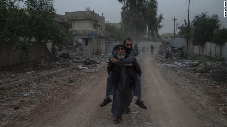 A man carries a sick relative on his back as they flee from their home in west Mosul&#39;s al Yarmouk neighborhood on April 11.
