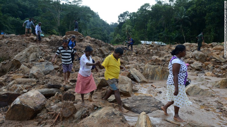 Sri Lankan villagers cross a landslide site as military rescue workers and villagers search for survivors in Athweltota village in Kalutara.