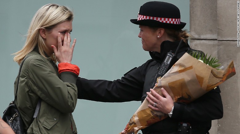 A woman reacts after asking a Police officer to lay flowers near London Bridge.