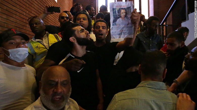 Protesters hold up pictures of missing loved ones Friday inside Kensington Town Hall.