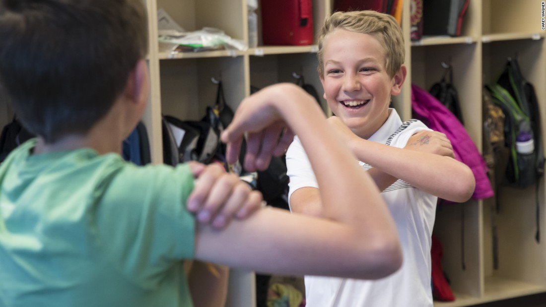 Blake Mechels [right) applies a temporary tattoo of Safiyo&#39;s flower to his arm.