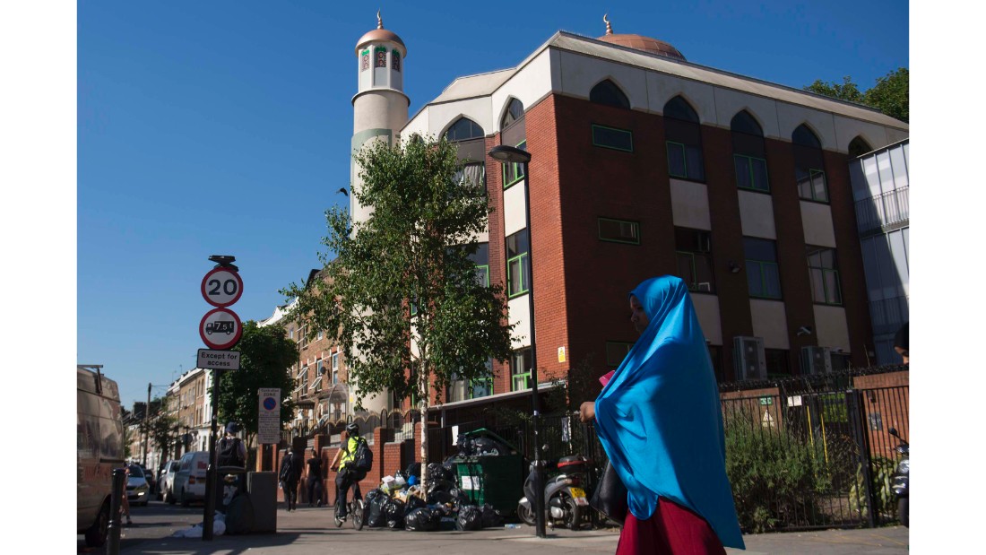 A woman in a blue hijab walks past the five-story red brick Finsbury Park Mosque -- the scene of Monday&#39;s attack.