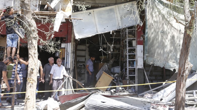 Syrians inspect the damage at the site of a suicide bomb attack in the capital Damascus&#39; eastern Tahrir Square district.