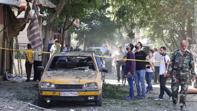 Syrian men look at a cordoned off area at the site of a suicide bomb attack in the capital Damascus&#39; eastern Tahrir Square district.