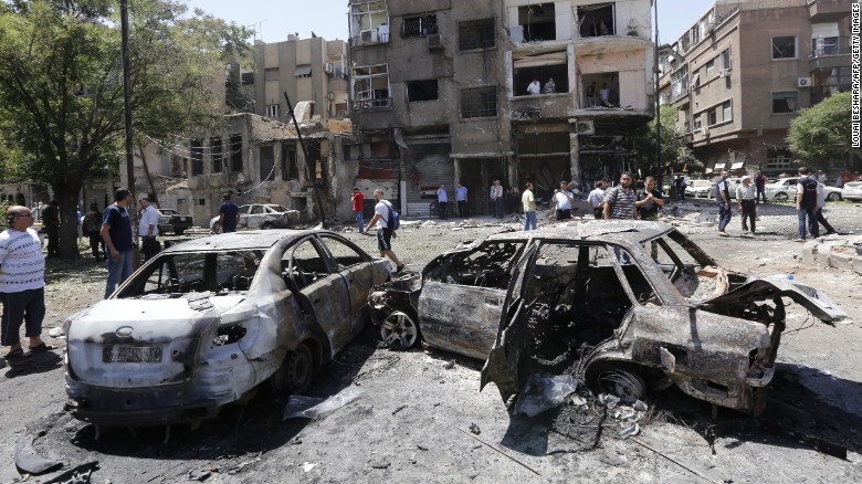 Charred vehicles are seen at the site of a suicide bomb attack in the Syrian capital&#39;s eastern Tahrir Square district.