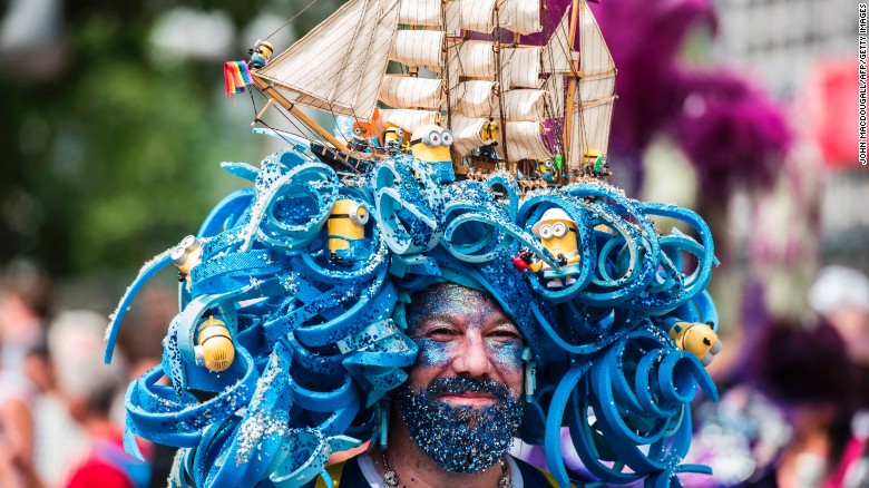 A man wears an intricate headpiece featuring a model ship and minions. 