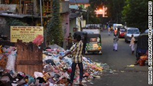 A Sri Lankan man throws trash onto garbage piled on a street in Colombo on June 26, 2017.