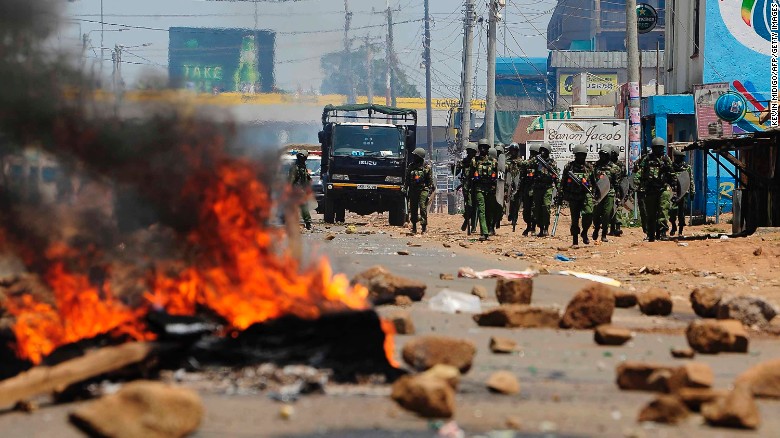 Kenyan security personnel walk towards burning barricades on a road in Kisumu on Wednesday.
