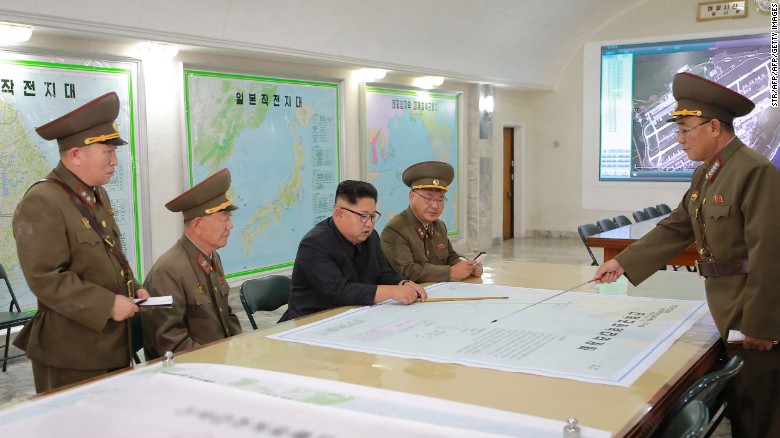 A picture from North Korea&#39;s official Korean Central News Agency (KCNA) released on August 15, 2017 shows North Korean leader Kim Jong Un (center) inspecting the Command of the Strategic Force of the Korean People&#39;s Army (KPA) at an undisclosed location. Some analysts say image on the screen appears to show runways at Guam&#39;s Andersen Air Force Base.