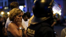 A woman gestures as she is escorted out by Spanish policemen outside a cordoned off area after a van ploughed into the crowd, killing 13 persons and injuring over 80 on the Rambla in Barcelona on August 17, 2017.