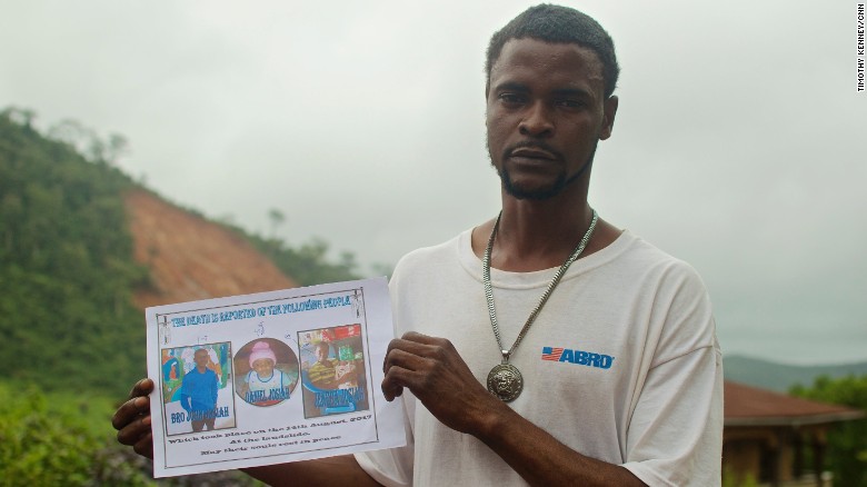 Gabriel Fattah Manga holds a poster showing the family members he lost in the mudslide that hit Sierra Leone&#39;s capital, Freetown.