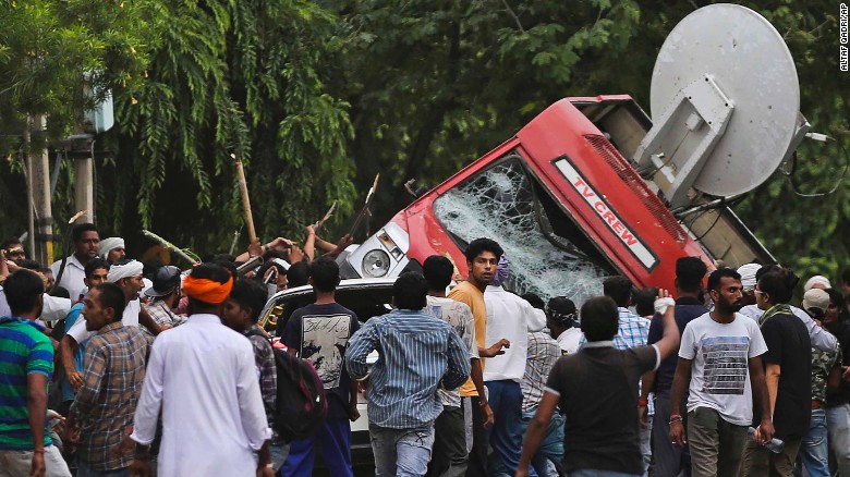 Dera Sacha Sauda sect members overturn an OB van on the streets of Panchkula, India, Friday, Aug. 25, 2017. 